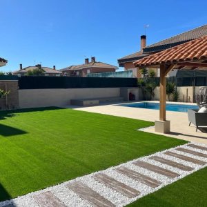 Jardín de chalet con césped artificial, piscina y pérgola de madera